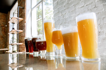 Glasses of dark and light beer and ale in sunlight on brick wall background. Cold delicious alcohol drinks are prepared for a big friend's party. Concept of holiday, fun, meeting, oktoberfest.