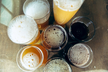 Top view of glasses of dark and light beer and ale on brick wall background. Cold delicious alcohol drinks are prepared for a big friend's party. Concept of holiday, fun, meeting, oktoberfest.
