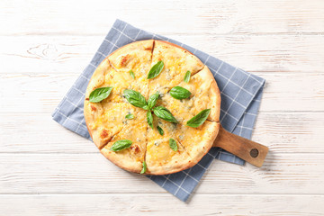 Towel, board, cheese pizza with basil on wooden background, copy space