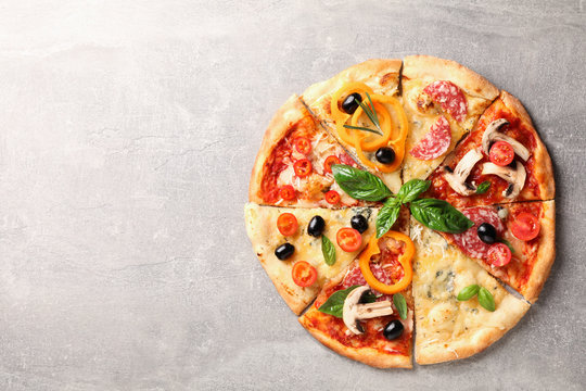 Delicious pizza with different pieces on grey background, space for text