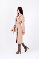 girl in a warm light coat on a white background. model in outerwear. brunette woman in a winter coat and sunglasses. beautiful girl in a casual coat. spring autumn collection