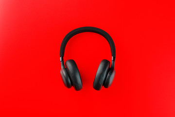 Fototapeta na wymiar Black bluetooth headphones on a red background top view. In-Ear Headphones for DJs