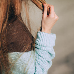 Fototapeta na wymiar fragment of a female woolen sweater close-up. Blonde girl in a blue knitted sweater. warm winter sweater. female hands