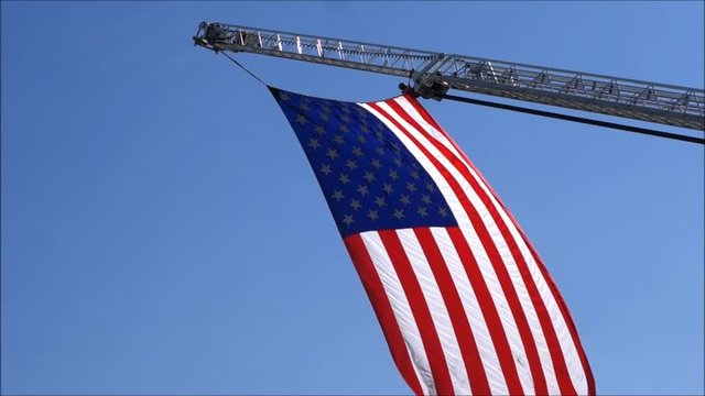 American flag hanging from fire truck ladder