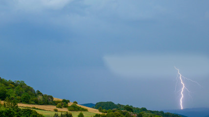 Thunderstorm with lightning over the hilly landscape