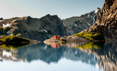 Stunning reflection of Andes mountains and Refugio Italia Manfredo Segre in Laguna Negra lake in Patagonia, Argentina. Winter backpacking. Pampa Linda trek. Hiking, camping and backpacking on iceberg 