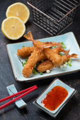 Whole deep-fried shrimps in breadcrumbs, studio shot over dark brown stone background