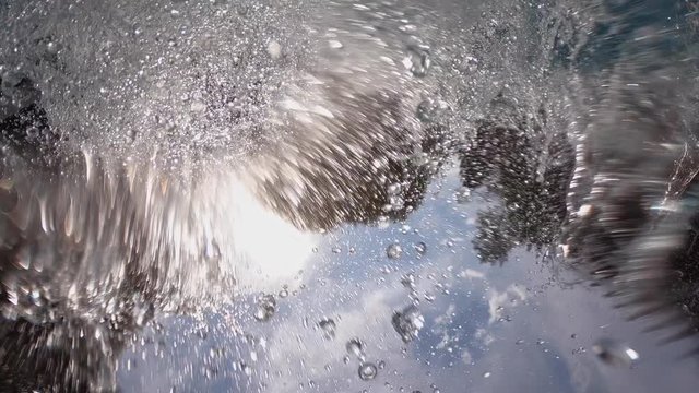 Teenager doing a gainer into pool over the camera following him overhead.