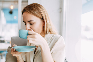  woman at work in a light coffee shop. young blogger girl with a mug of coffee.