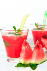 Healthy watermelon smoothie with of watermelon in glasses on a wood background. Decorated with mint leaves and ice.