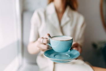  atmospheric coffee shop and stylish dishes. hot mug of coffee in the hands of a young girl.