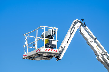 Bucket truck high up of a crane with blue sky