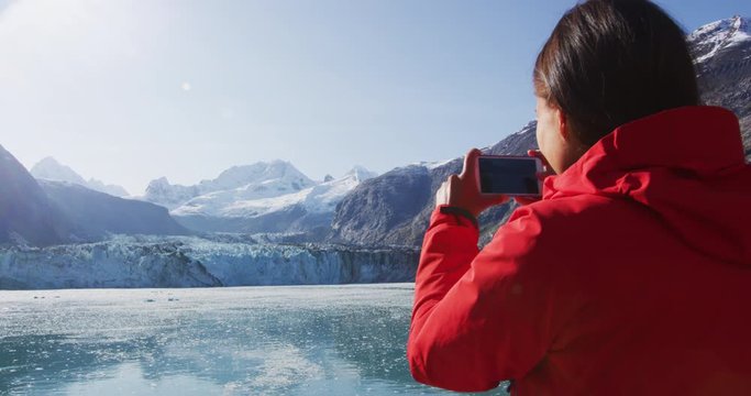 Alaska cruise ship passenger photographing glacier in Glacier Bay National Park, USA. Woman tourist taking photo picture using mobile cell smart phone on travel vacation. Johns Hopkins Glacier.