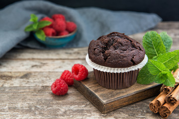 Chocolate muffin with mint leaves and fresh raspberries on the table