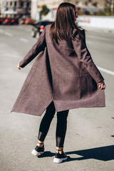 Young elegant girl posing on a city street. girl walks around the city on a clear autumn day. beautiful business autumn trend, hands closeup, details.