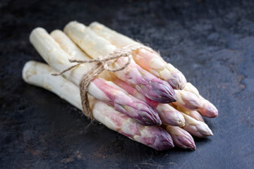 Roher wei&szlig;er Spargel mit violetten K&ouml;pfen angeboten als closeup auf einem alten Blech mit Textfreiraum 