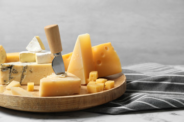 Fototapeta premium Different types of delicious cheese in plate on marble table against light background, space for text