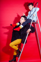 pretty young mother with little son on ladder on red background posing cheerful happy smiling, lifestyle people concept