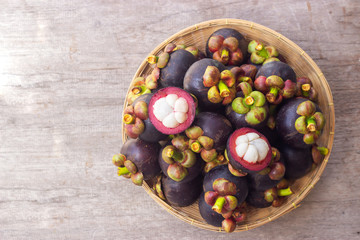 Fresh mangosteen in bamboo basket. Top view with copy space on wooden table. Healthy and sweet fruit. High vitamins.