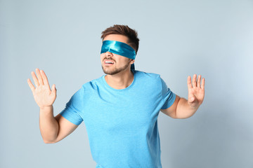 Naklejka premium Young man with light blue blindfold on grey background