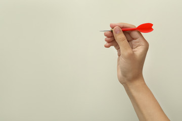 Woman holding red dart on light background, closeup. Space for text