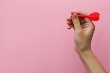 Woman holding red dart on pink background, closeup. Space for text