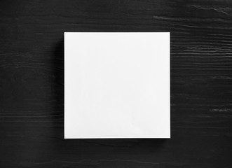 Stack of blank paper sheets for brochure on black wooden background, top view. Mock up