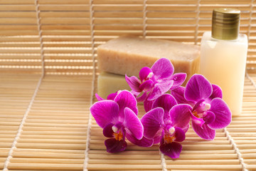 Beautiful orchid flowers and soap on bamboo mat, space for text