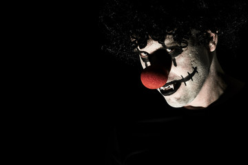 Close up portrait of a scary clown in a black wig and makeup. A man in a costume of a creepy clown...