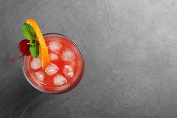 Glass of tasty refreshing cocktail on grey background, top view. Space for text