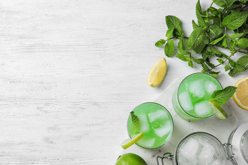 Flat lay composition with delicious cocktails on white wooden table. Space for text