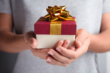 Woman holding beautiful gift box with bow, closeup