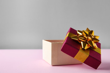Beautiful open gift box on pink table. Space for text