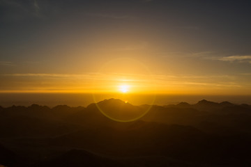 The meeting of the dawn in the mountains. Early morning, romantic landscape. The sun is showing on the horizon. Sunrise in the mountains