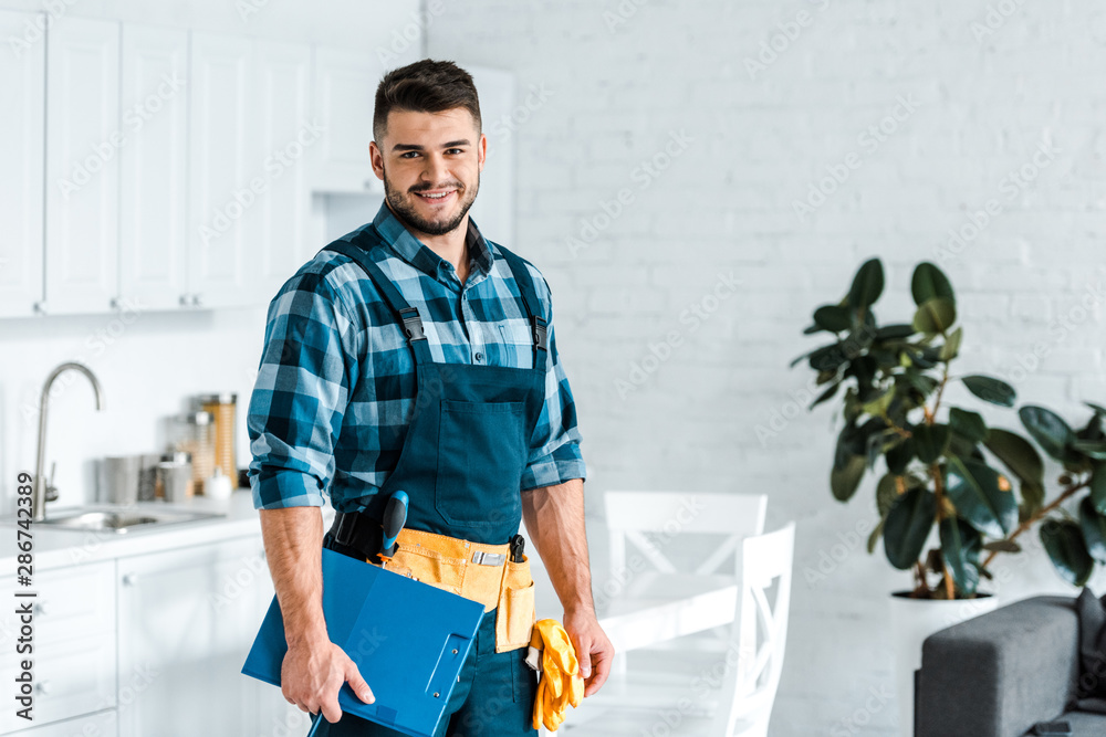 Wall mural happy bearded workman standing and holding clipboard