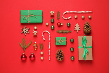 Christmas tree branches and festive decoration on red background, flat lay
