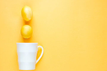 Obraz na płótnie Canvas Flat layout. Mug and two lemons on a yellow background.