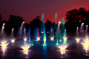 Multicolored city fountain on a background of sunset sky.