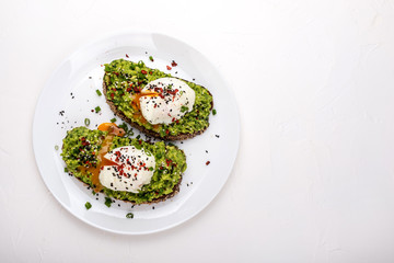 Poached eggs with avocado guacomole on brown bread with sesame seeds. Healthy breakfast on a white background. Copy space.