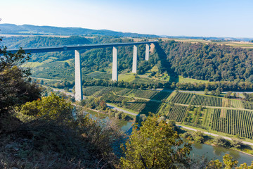 View on high freeway viaduct bridge across Mosel river valley and terraced vineyards, road network...