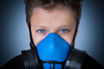 Young boy wearing gasmask, respirator portrait. Effects of worldwide air pollution, industrial...