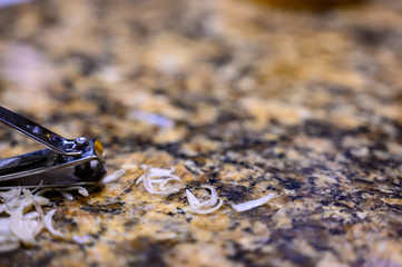 Pile of fingernail and toenail clipping next to a metal cutter