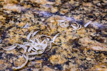 Pile of fingernail and toenail clipping next to a metal cutter