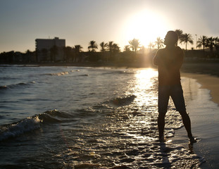 Silhouette of a young man on the beach at sunset.
