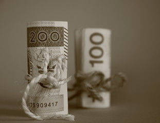 Banknotes of Polish zloty, 200 and 100 zloty, rolled and tied with  twine isolated, close up, monochrome sepia color
