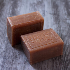 two pieces of brown natural soap on a wooden surface