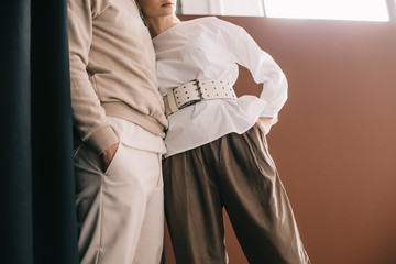 cropped view of stylish couple standing with hands in pockets near curtain on black