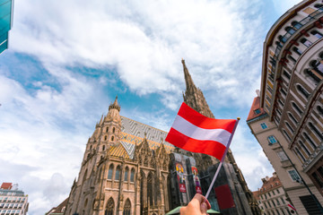 Saint Stephen's Cathedral on the central square in Vienna with the flag of Austria in female hands, Austria