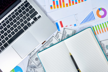 Business Concept. Laptop, graph and banknote dollars with notebook and pen