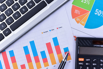Laptop and pen with business charts, graphs, statistic and documents background for education and business concepts